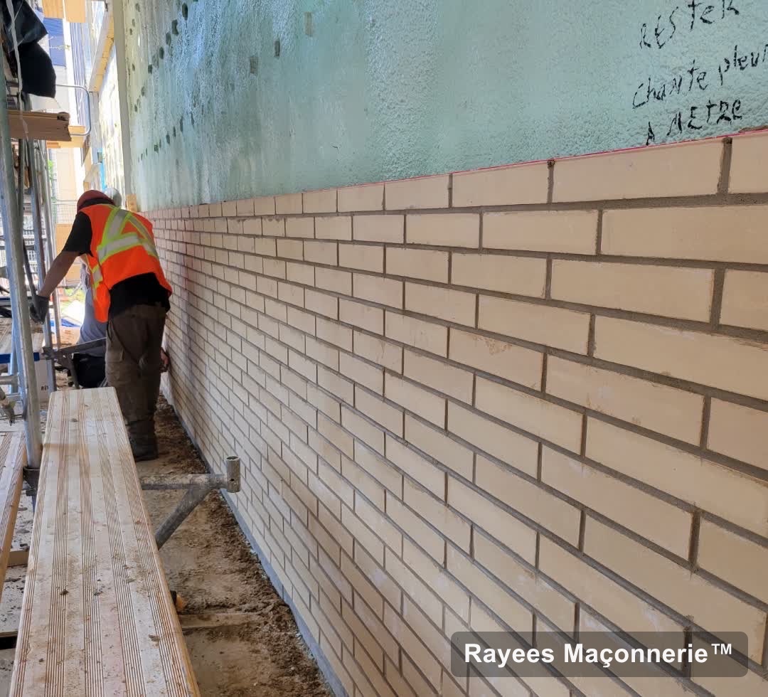 Équipe posant un long mur de brique crème