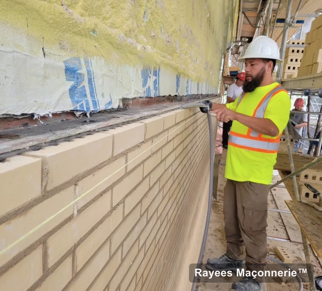Maçon au niveau laser sur un mur de brique crème